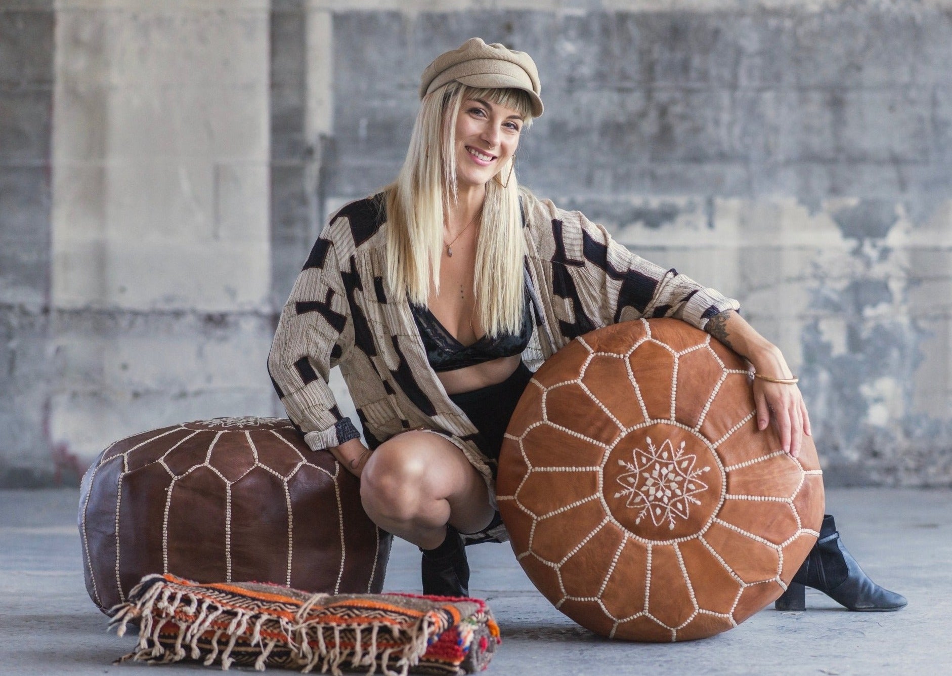 industrial space is the backdrop to a setting where beautiful blond babe poses between two moroccan floor cushions and a moroccan textile woven from a female weaving cooperative.