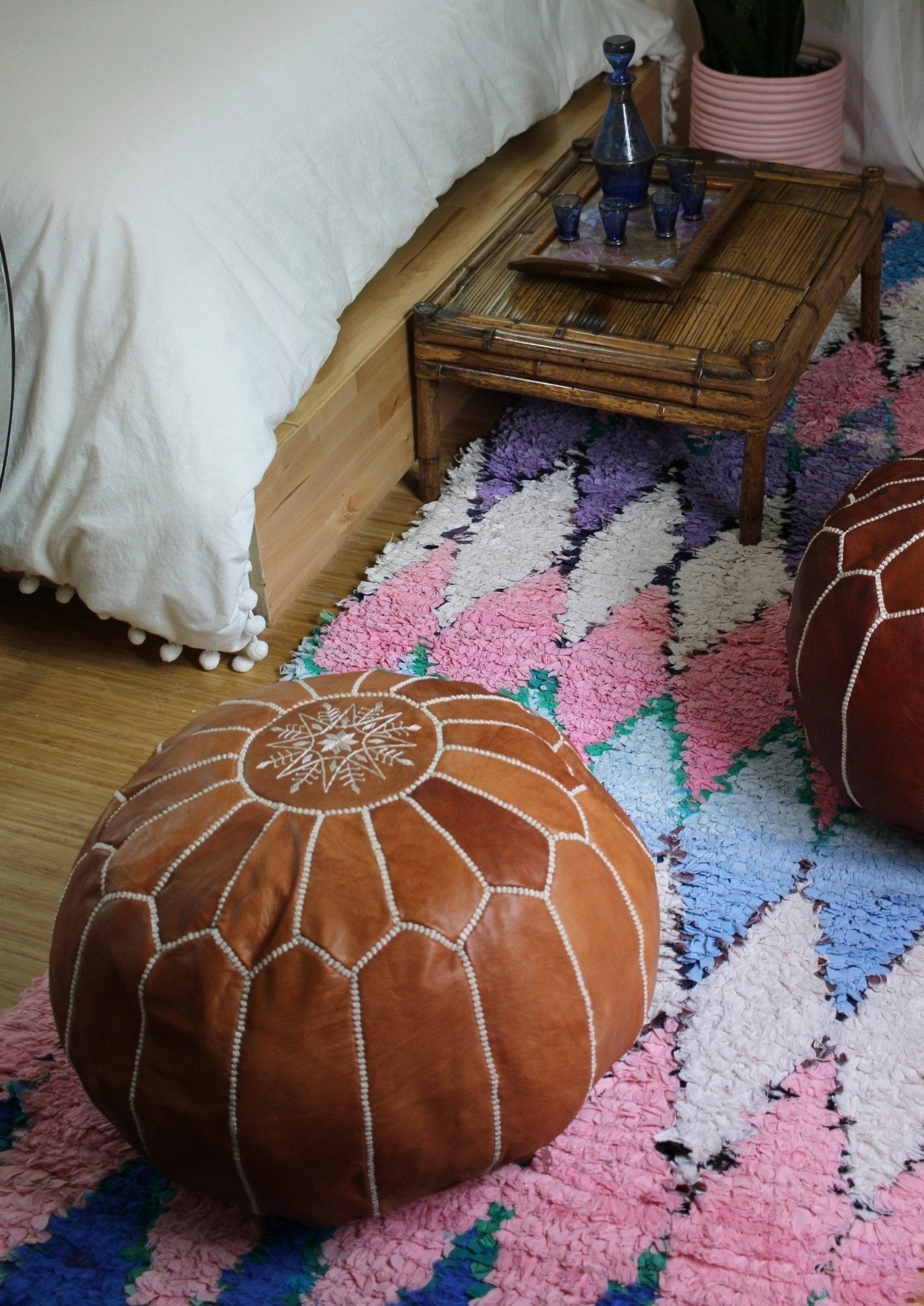 playful girls room with two leather poufs, a boucherouette rug and tea set sitting on a bamboo table. Pink accents match the potted plant and rug. Dream room.