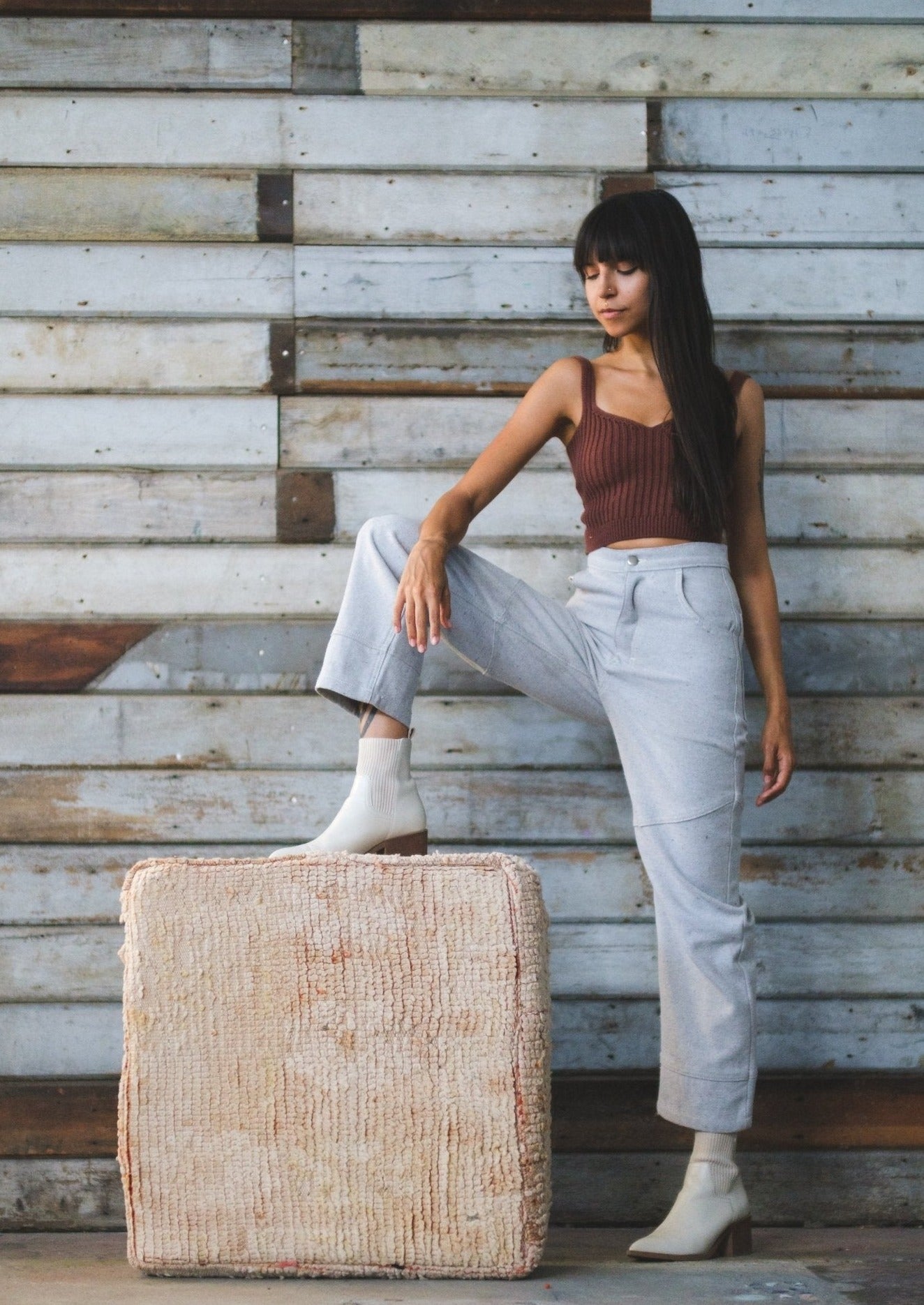 washed out white moroccan floor cushion sits on ground while girl props her foot on it. She is relaxed at ease wearing soluna collective clothing made from organic fibers