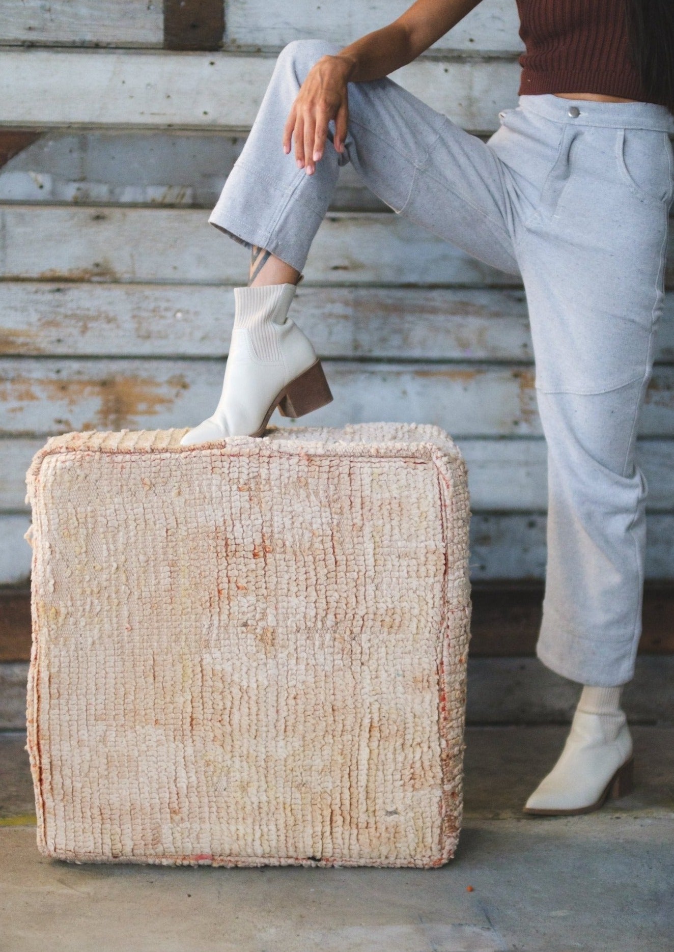 Girl points toe of white boot on top of moroccan cushion with washed out motifs