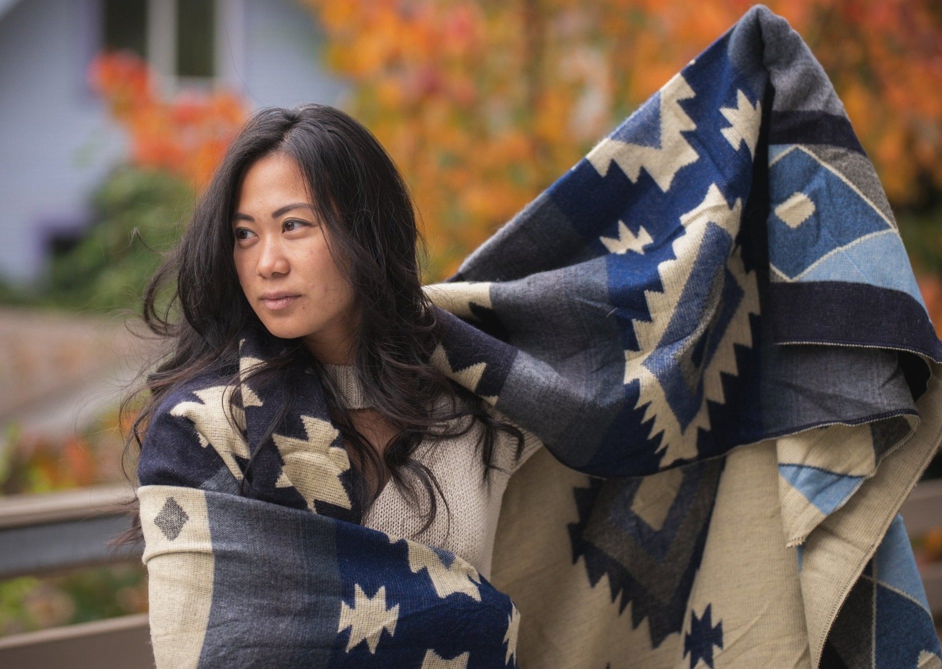 asian girl goes for a walk in the fall with her soft blue alpaca blanket her hair is long and curled, she looks at peace