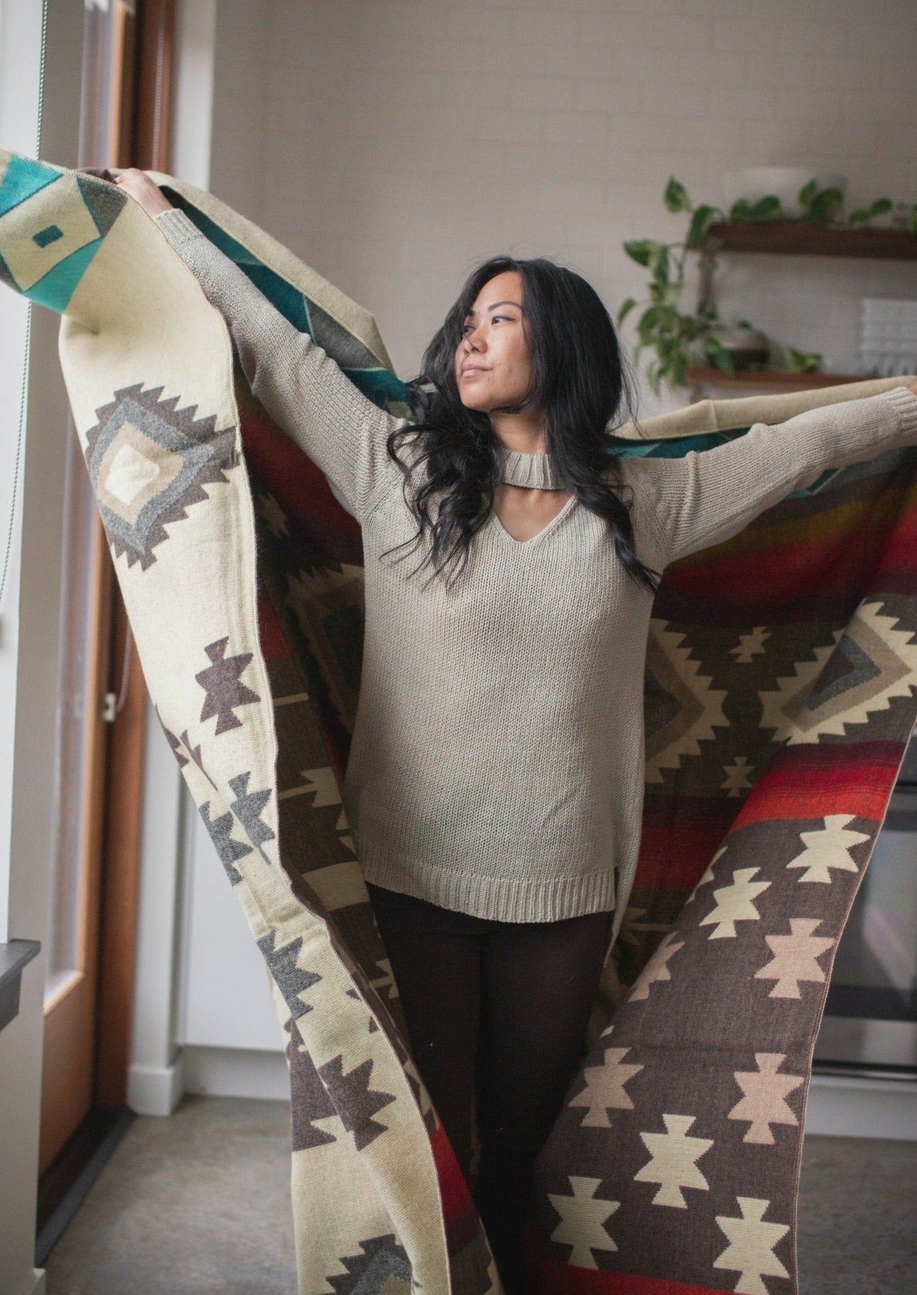 Asian girl wears comfortable sweater and dances around in her apartment with her alpaca blanket. 