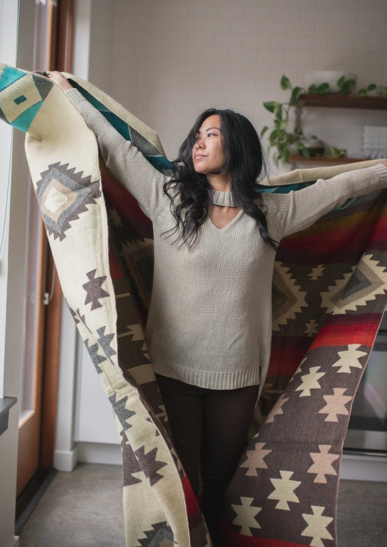 Asian girl wears comfortable sweater and dances around in her apartment with her alpaca blanket.