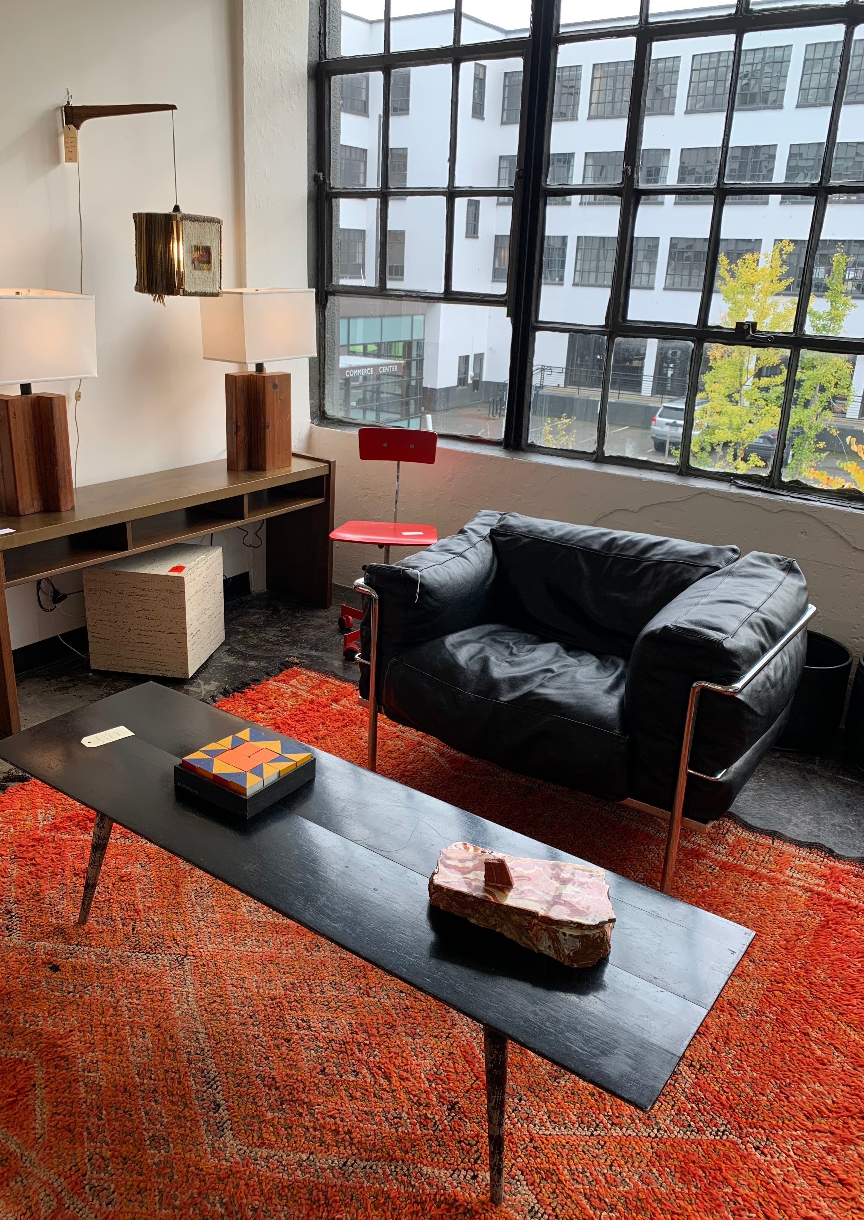 red rug in modern loft apartment with leather chair and black coffee table with large windows