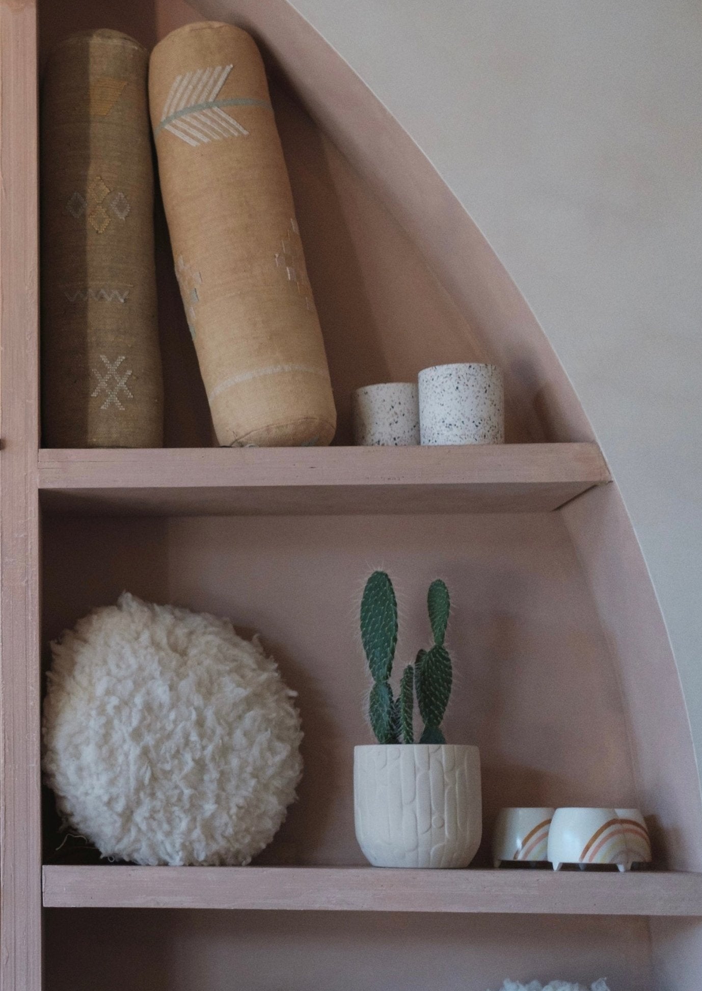 cactus silk pillow paired with sheep pillow displayed in portland shop origin story inside an arch wall. cactus plant and white accent pot holders sit next to them. 