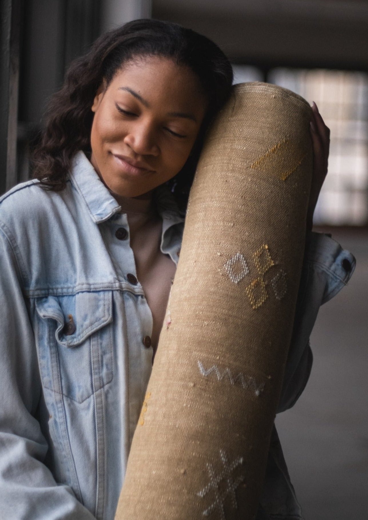 vegan friendly fiber soft cozy and excellent back support. black girl holds pillow lovingly with berber symbols stiched. 