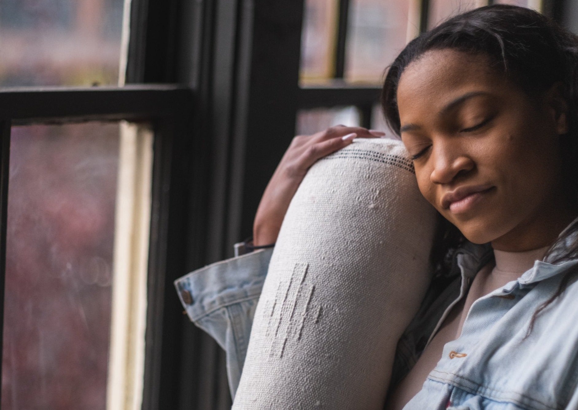 African American girl closes her eyes in a deep serene moment touching her face to the silky soft pillow made in morocco with cacti fibers 