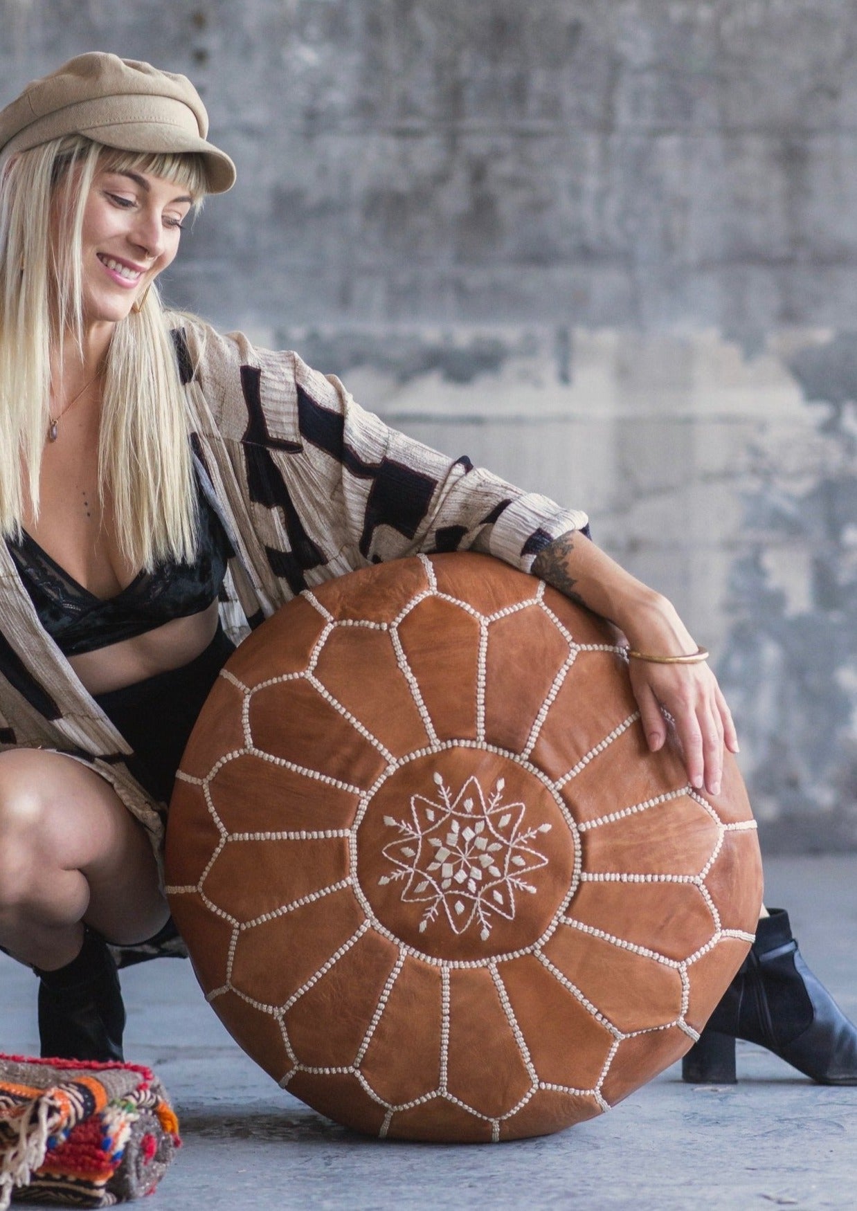 gorgeous girl with long blond hair and bangs wrests her arm on moroccan pouf lovingly. 