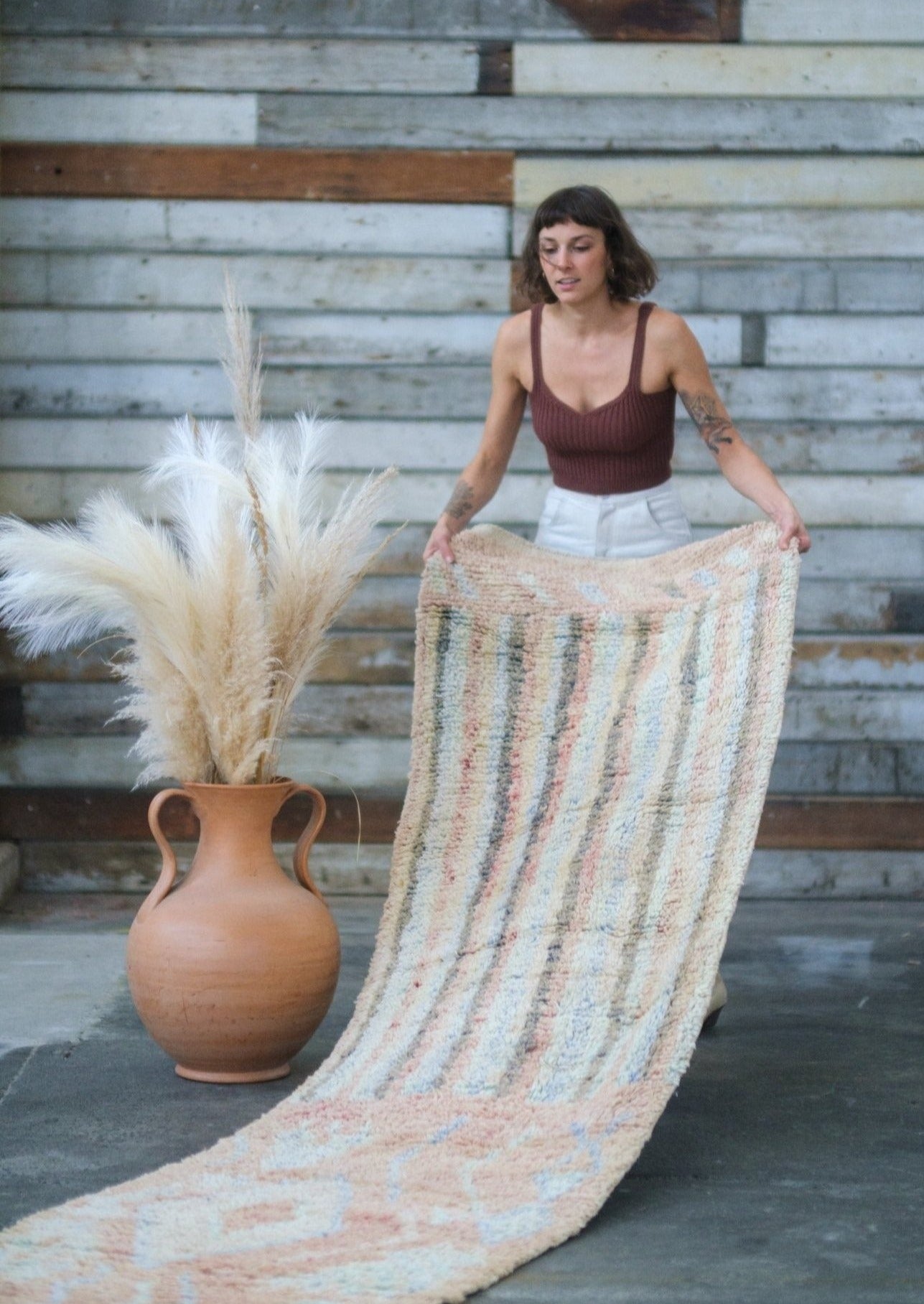 girl unravels rug to reveal the design while waring soluna collective clothing made from organic sustainable materials in an urban rustic scene 