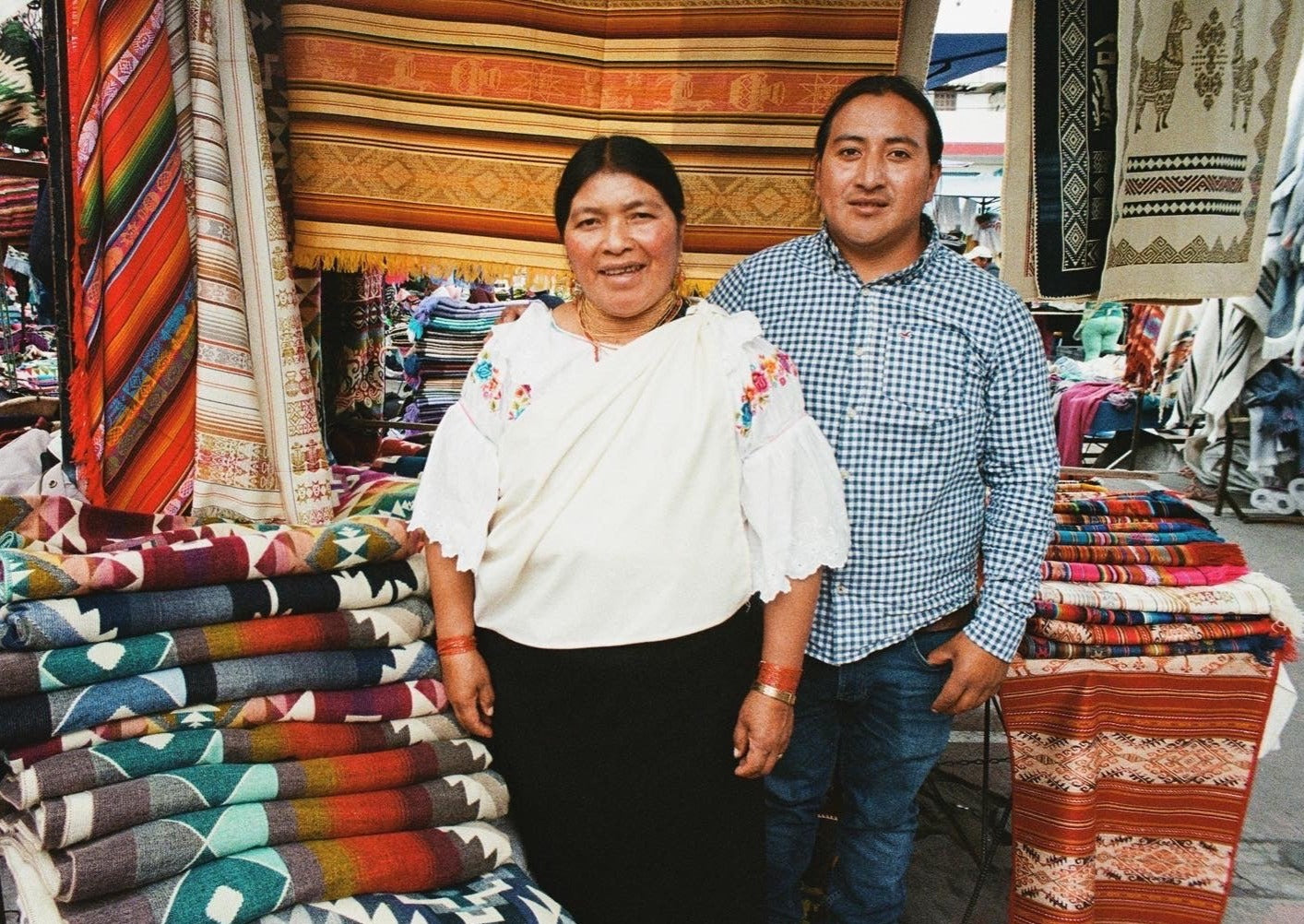 artisans of Ecuador captured on film at a market in Otavalo surrounded by their handmade alpaca blankets