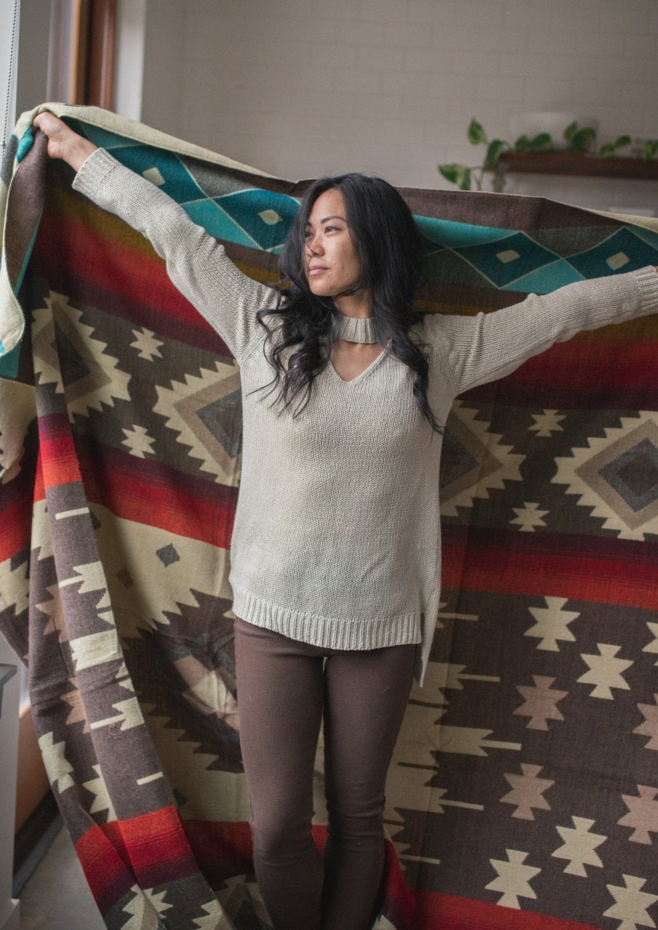 Asian girls arms are wide open holding her cozy alpaca blanket made in ecuador. 